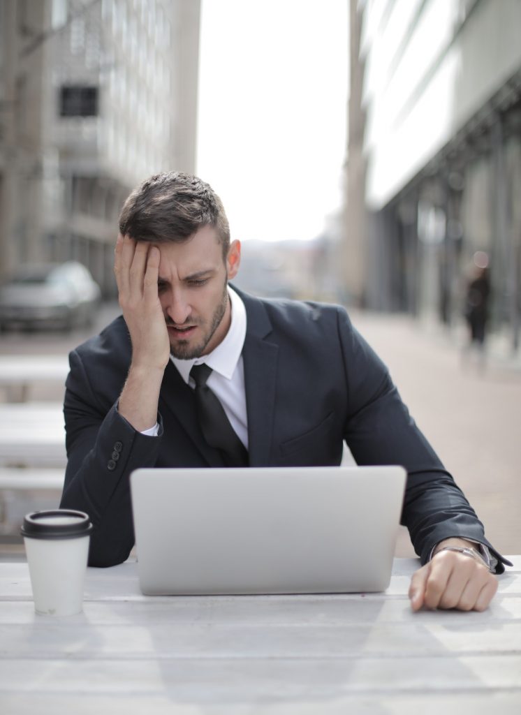 A tired man looking at a laptop screen